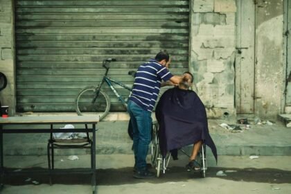 Seorang pria membantu mencukur rambut orang lain yang duduk di kursi roda, Oktober 2024. (qsm/ho/mediapesan)