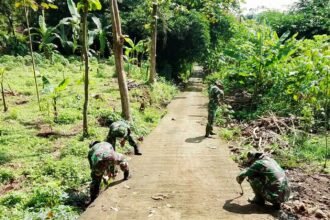Babinsa Koramil 03/Mojosongo sedang membersihkan rumput liar di bahu jalan Desa Metuk, Kecamatan Mojosongo, Kabupaten Boyolali, (3/4/2025).