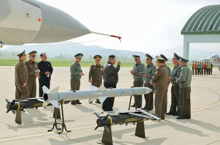 Pemimpin Tertinggi Kim Jong Un terlihat menginspeksi rudal di sebuah pangkalan udara, dikelilingi oleh perwira tinggi militer, Mei 2025. (kcna/ho/mp)