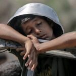 Seorang anak yang tertidur dalam antrian kelaparan, mengambil panci sebagai helm... untuk memimpikan sepotong makanan yang rasanya belum pernah ia ketahui, 27 Juli 2025. (Journalist Ali Abu Aqa/HO/MP)