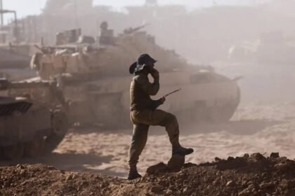 Seorang prajurit dengan alat komunikasi tampak di tengah debu tebal saat kendaraan lapis baja bergerak di pinggiran Kota Gaza, menandai dimulainya operasi darat IDF untuk merebut benteng Hamas.