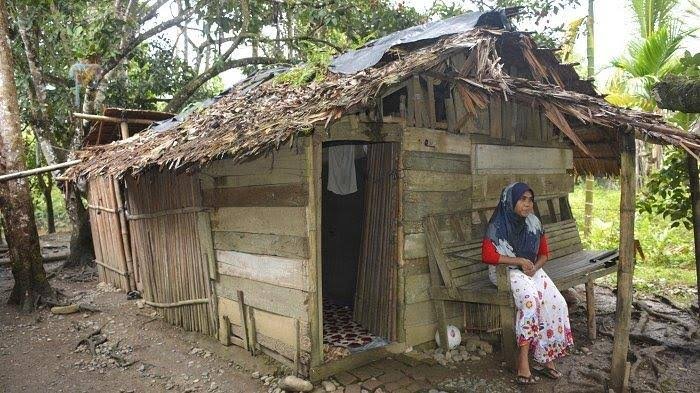 Seorang warga Aceh duduk di depan rumahnya yang tidak layak huni — potret nyata kesenjangan di tengah tanah yang kaya sumber daya alam.