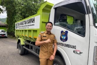 Bupati Enrekang H. Muh. Yusuf Ritangnga berpose di depan armada dump truck baru yang resmi dioperasikan untuk memperkuat layanan kebersihan daerah.