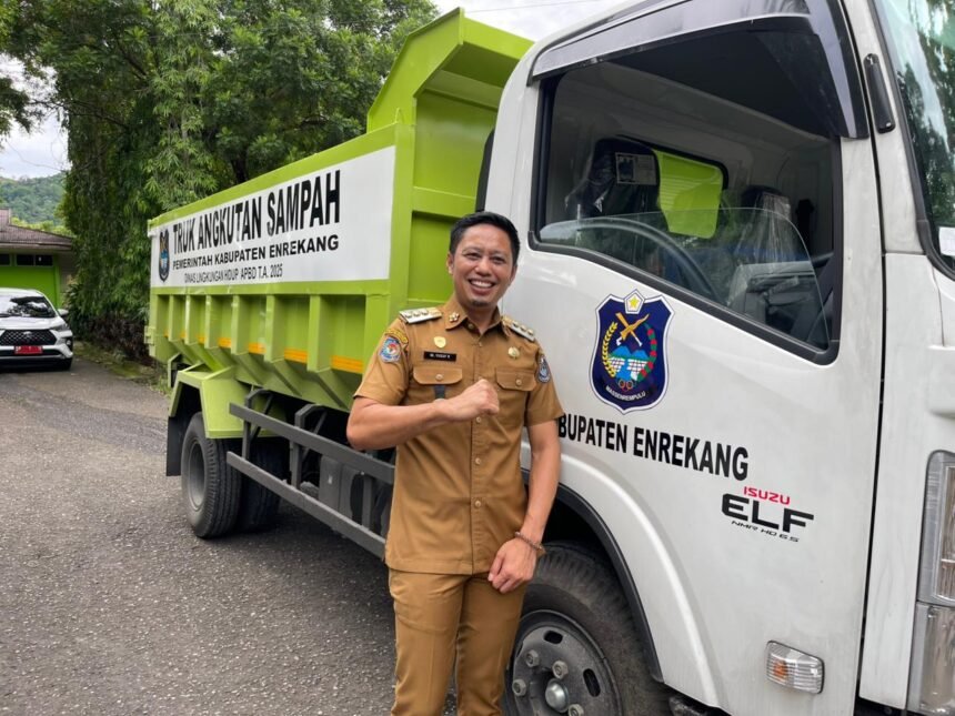 Bupati Enrekang H. Muh. Yusuf Ritangnga berpose di depan armada dump truck baru yang resmi dioperasikan untuk memperkuat layanan kebersihan daerah.