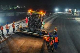 Pekerja jalan tol melakukan pengaspalan malam hari dengan alat berat untuk menjaga kualitas dan kelancaran proyek infrastruktur.