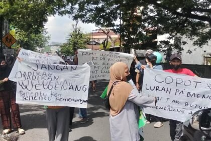 Warga RT 05 RW 05 Pa’baeng-baeng turun ke jalan membentangkan spanduk protes, menuntut keadilan dan pencopotan lurah usai pembatalan hasil pemilihan Ketua RT.