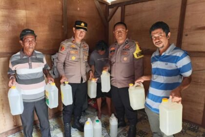 Petugas Polsek Namlea menunjukkan barang bukti 32 jerigen miras tradisional jenis sopi hasil razia KRYD di Kecamatan Namlea, Kabupaten Buru, jelang Ramadan 2026.