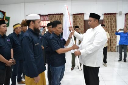 Bupati Maros menyerahkan bendera pataka kepada Ketua SMSI Maros usai prosesi pelantikan pengurus di Kantor PPK Maros, Ahad (1/3/2026).