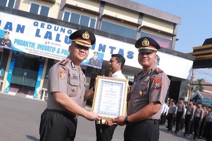 Kapolres Lamongan AKBP Adhytiawarman Gautama Putra kepada Kapolsek Solokuro AKP Joko Suprianto dalam upacara penghargaan di halaman Mapolres Lamongan, Senin (7/9/2026).