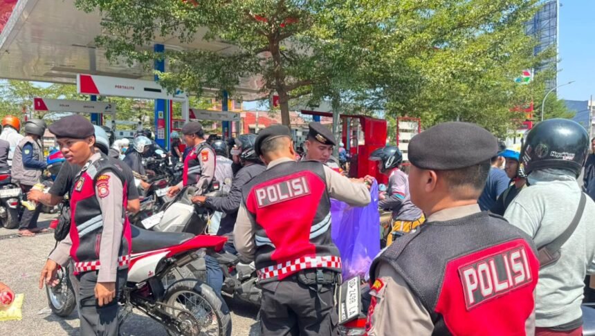 Personel Polresta Gowa turun langsung mengatur lalu lintas dan juga membagikan air minum dan roti kepada warga yang menunggu giliran mengisi BBM, Minggu (13/9/2026).